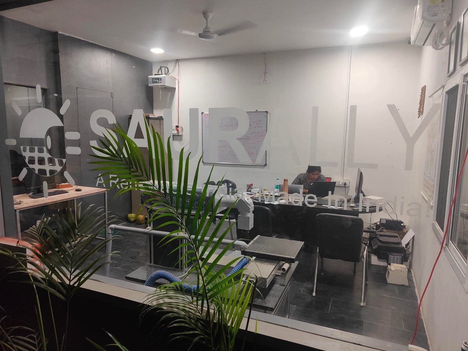 Inside the Saurally office, with the Saurally logo and 'A Renewable India, Made In India' etched on the glass wall